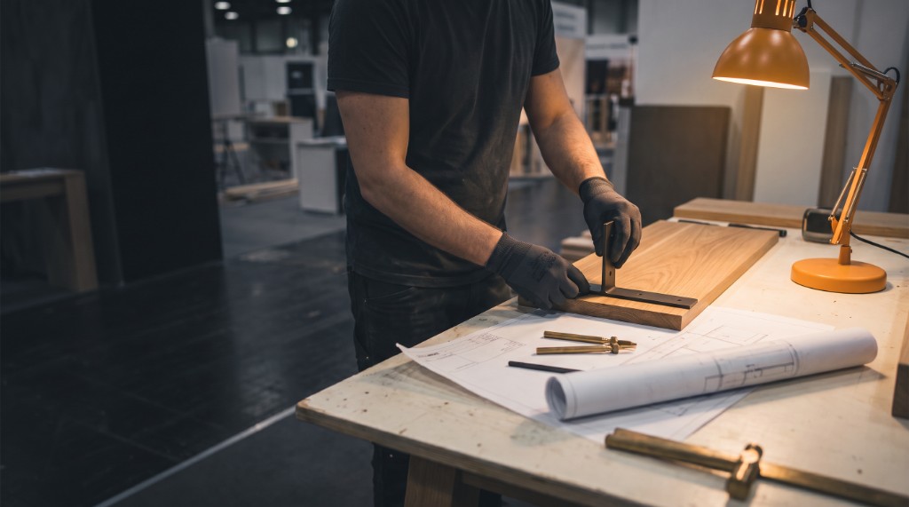 Craftsman assembling an exhibition stand with technical drawings